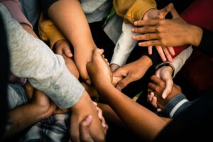 A close-up of diverse hands coming together in the center, symbolizing unity and teamwork.